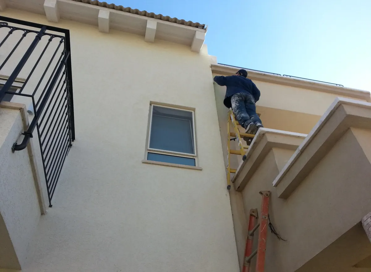 Exterior window cleaning on an upper story, with the cleaner on a ladder