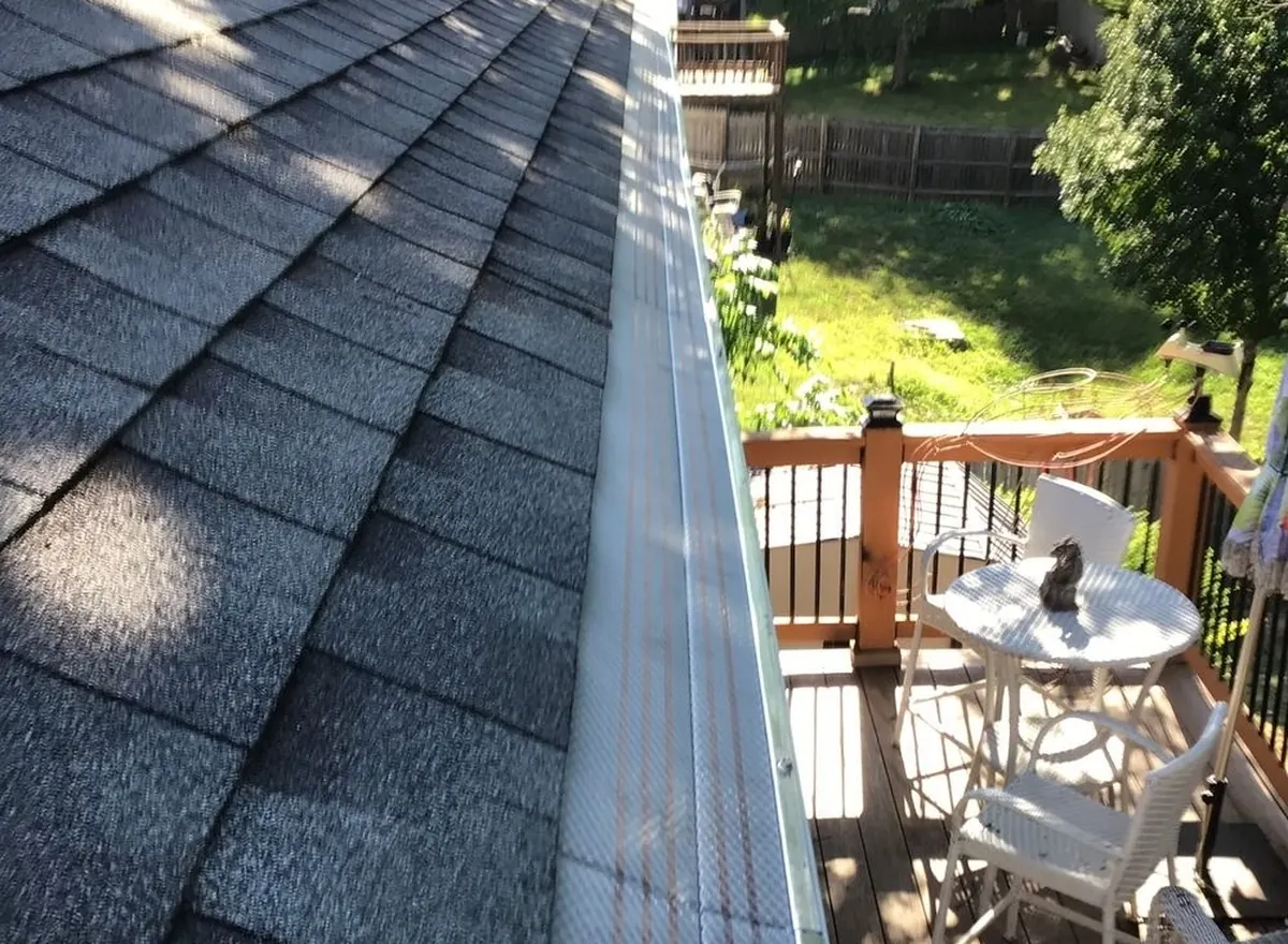 Clean gutter running along a shingle roof toward the downspout