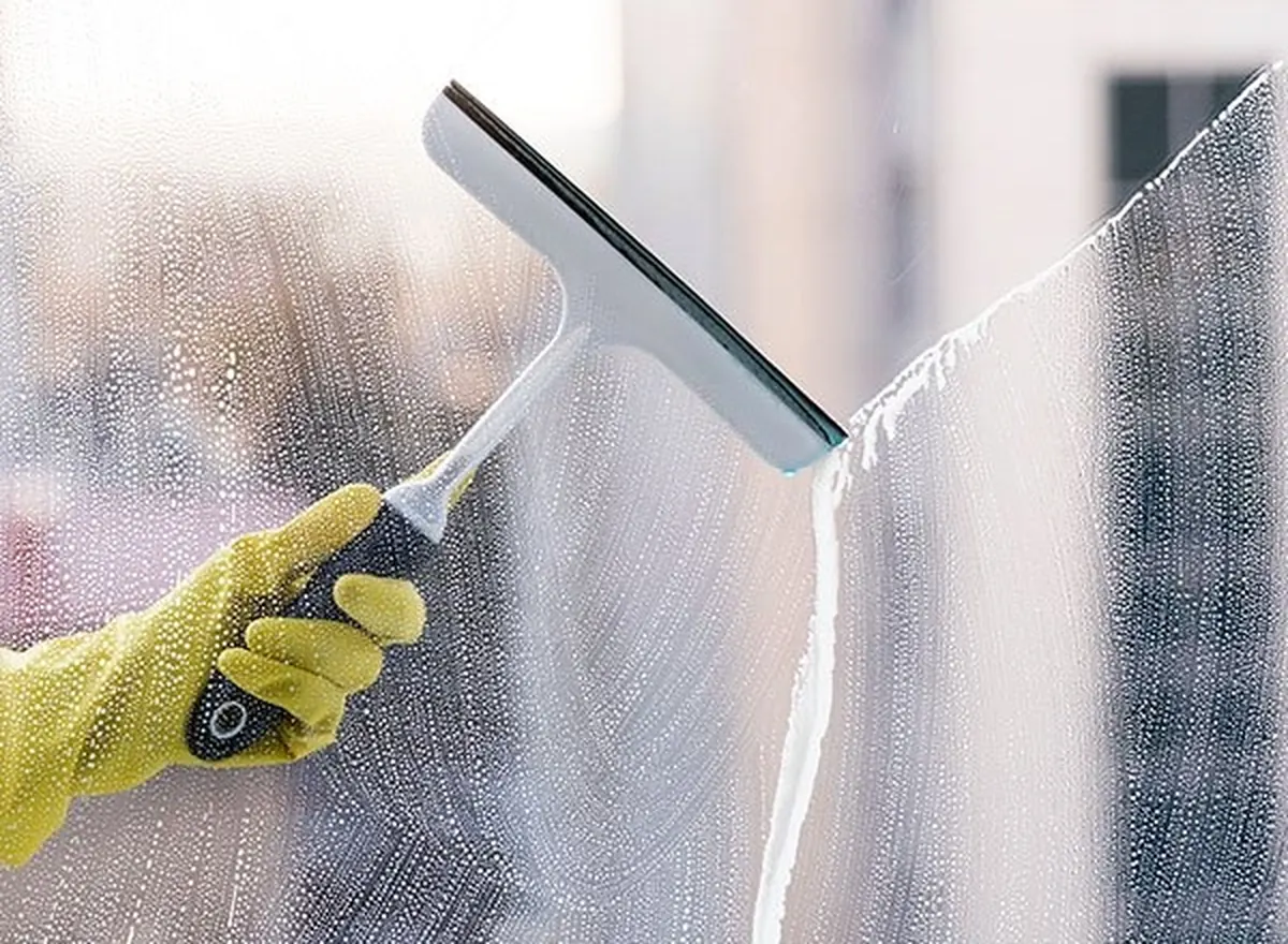 Squeegee clearing soapy water from a large office window