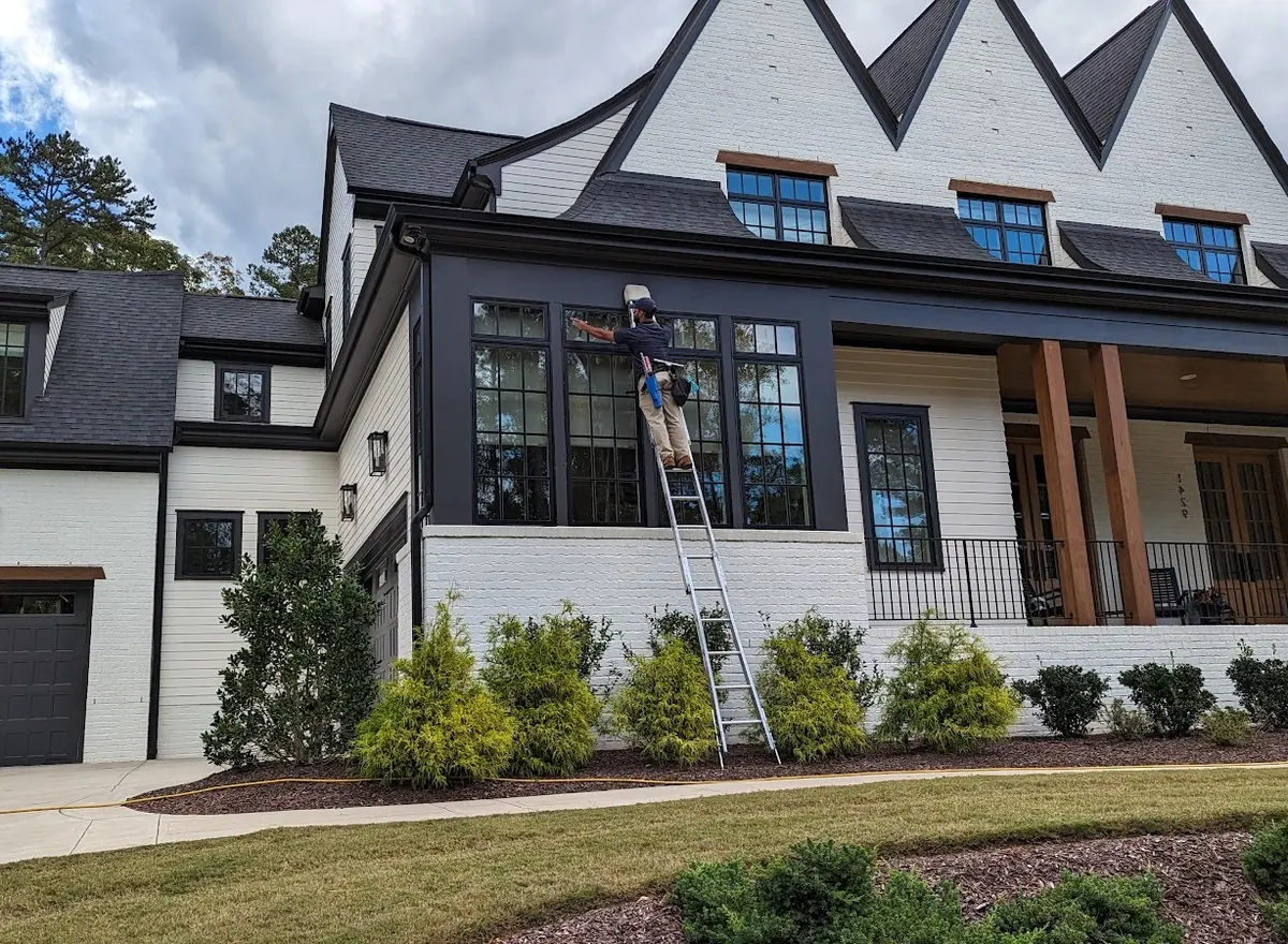 Residential window cleaning on a two-story home, with the cleaner on a ladder
