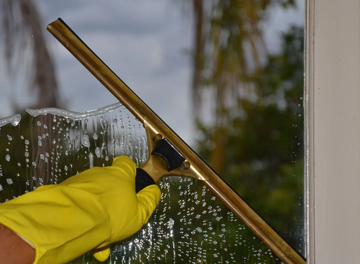 Gloved hand squeegeeing a window during a window cleaning job