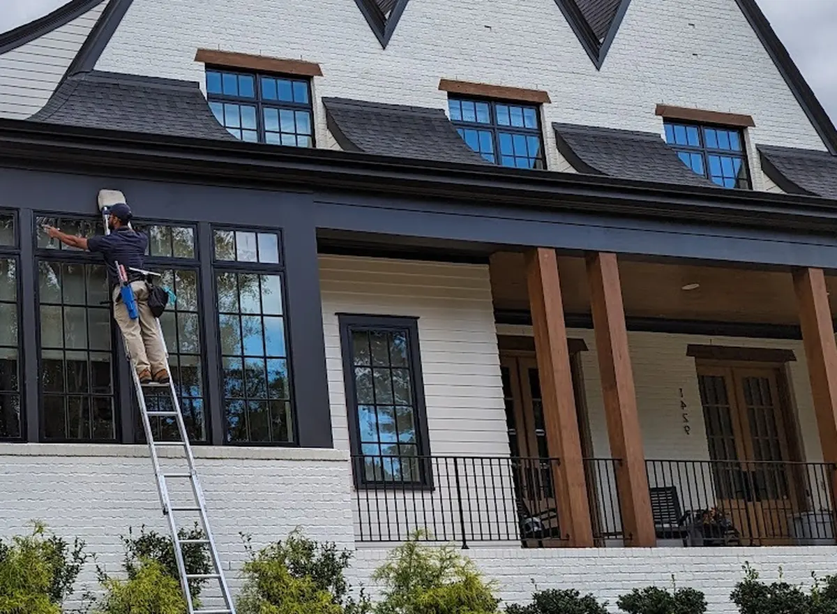 Two-story house with windows being cleaned from a ladder