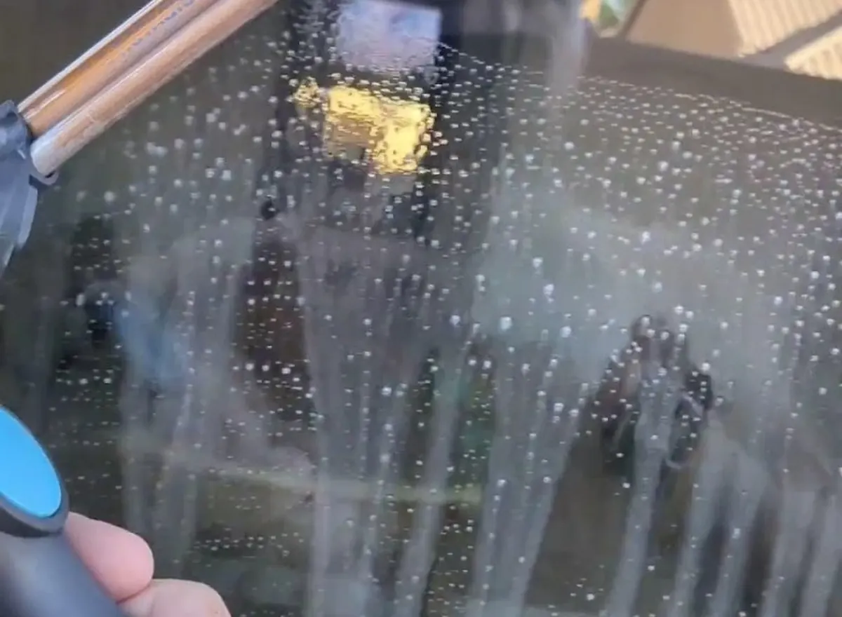 Close-up of a window being washed with a scrubber and squeegee